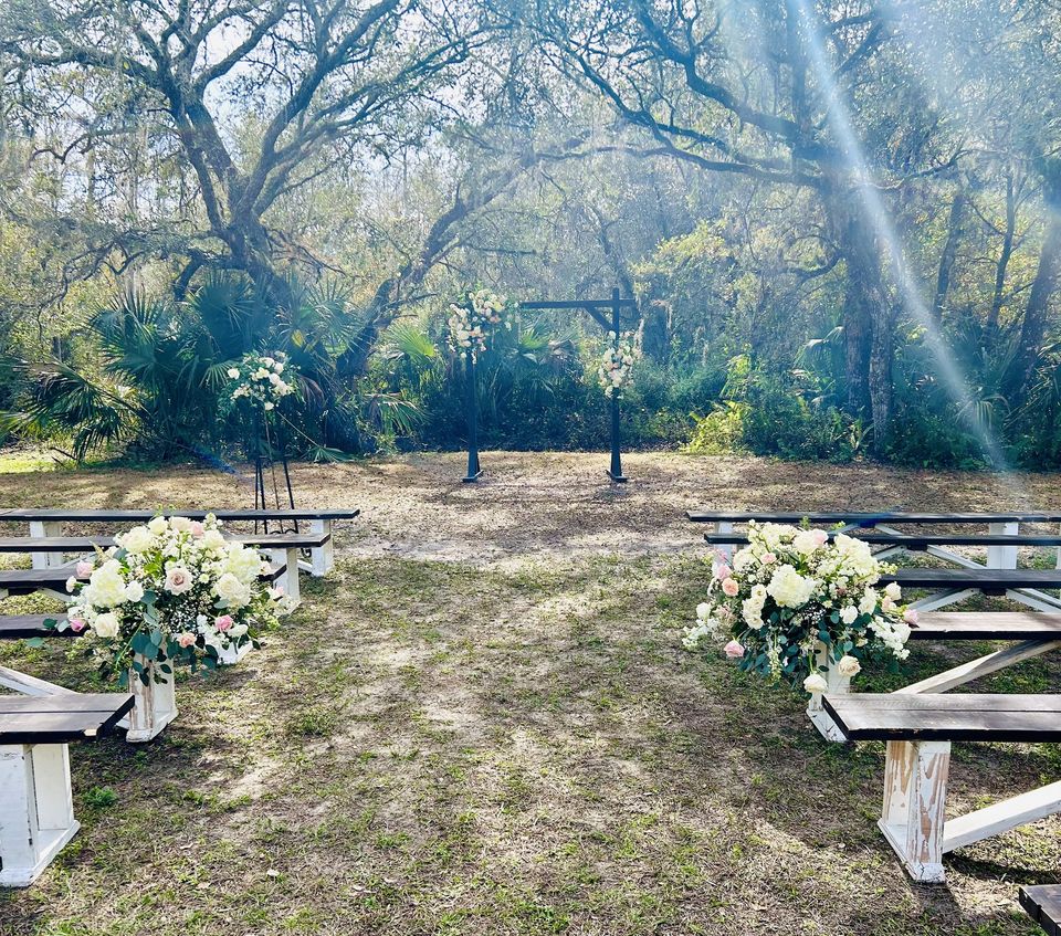 Outdoor ceremony with blush and white floral ground arrangements flanking the aisle