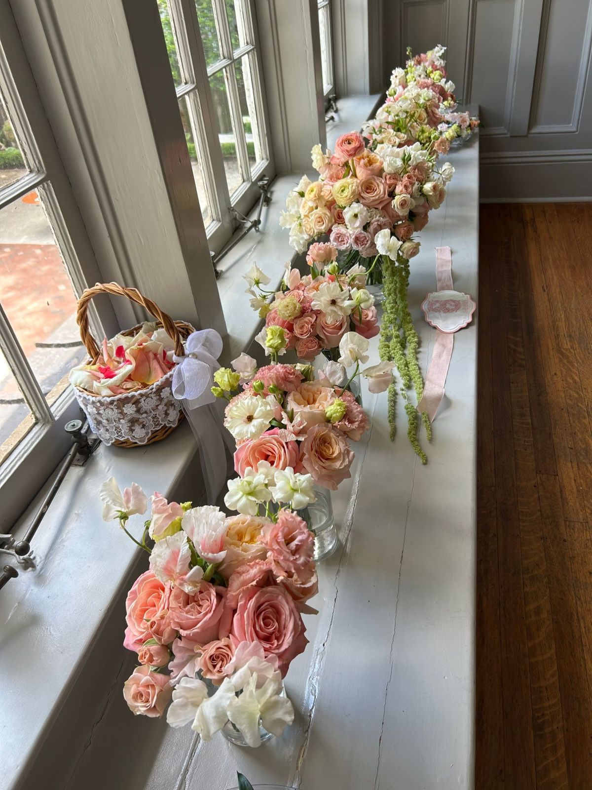 Blush and peach wedding bouquets lined up on a sunlit windowsill