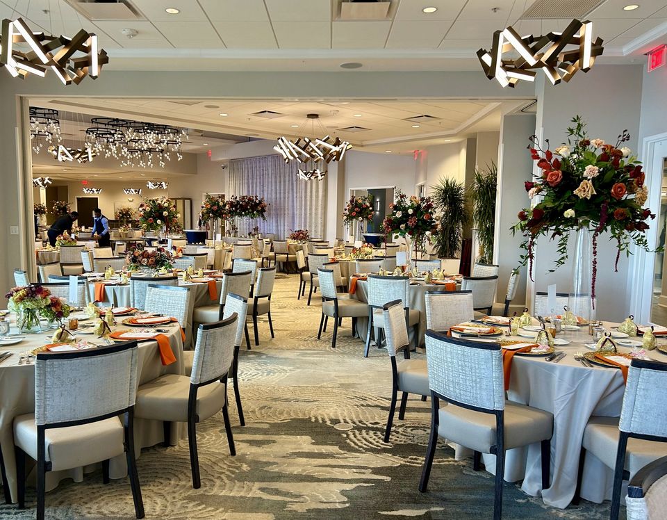 Indoor reception with tall autumn-toned arrangements and modern fixtures