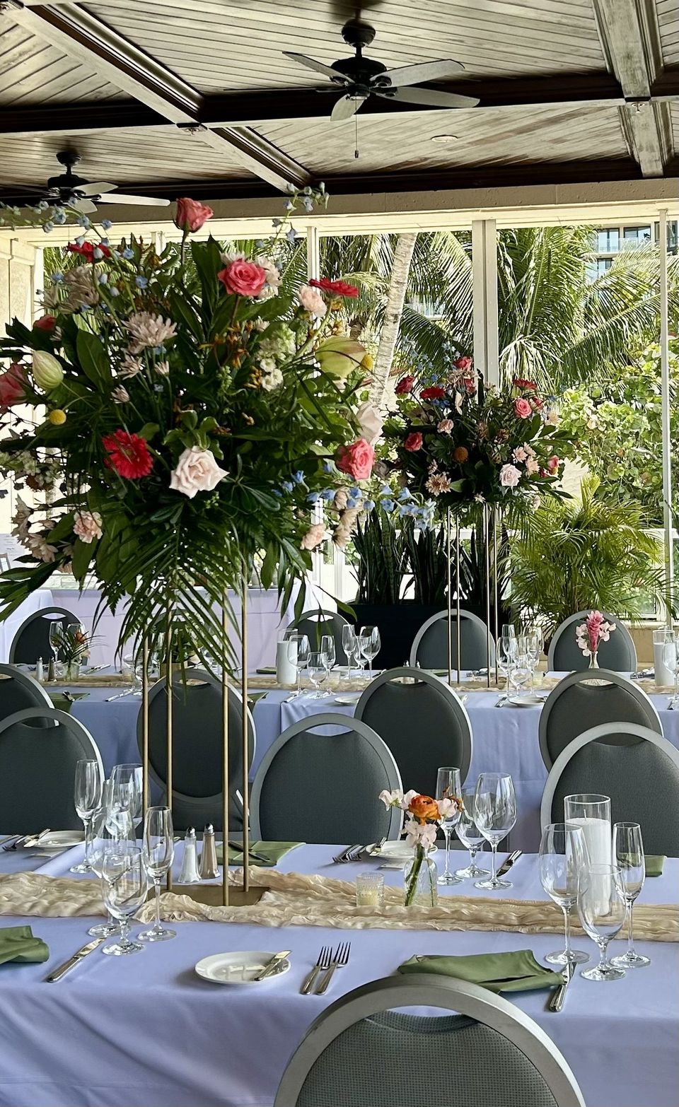 Tall pink and coral floral centerpieces on a long reception table